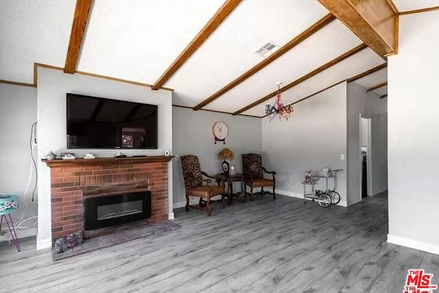 living room with hardwood / wood-style flooring, vaulted ceiling with beams, and a brick fireplace