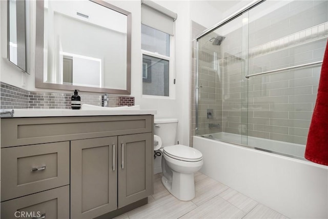 full bathroom with vanity, bath / shower combo with glass door, tile patterned flooring, toilet, and tasteful backsplash