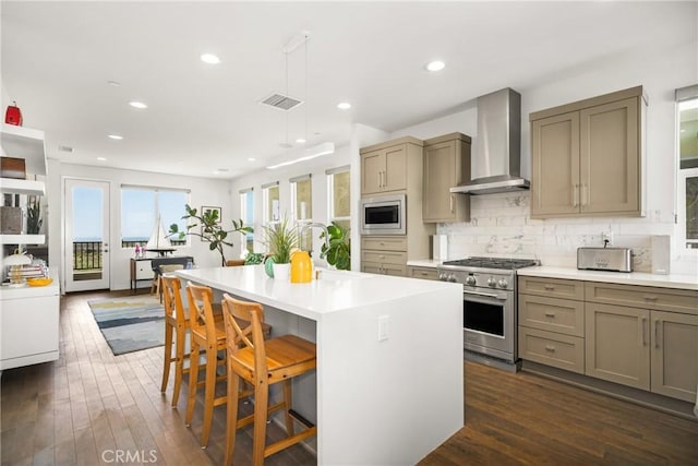 kitchen featuring appliances with stainless steel finishes, a center island, dark hardwood / wood-style flooring, and wall chimney exhaust hood