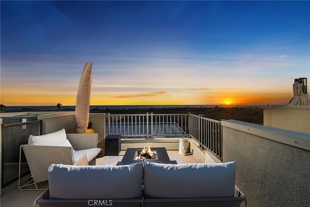 balcony at dusk featuring an outdoor living space with a fire pit