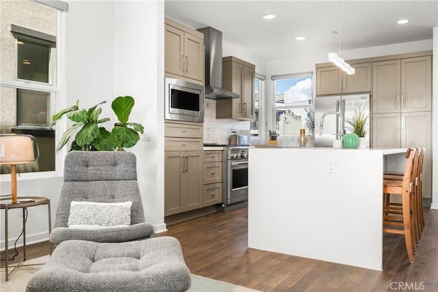 kitchen with a center island, wall chimney range hood, dark hardwood / wood-style floors, built in appliances, and decorative light fixtures