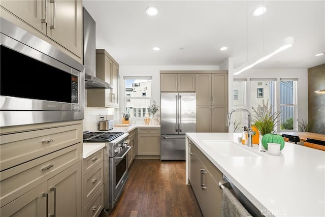 kitchen with dark hardwood / wood-style flooring, a wealth of natural light, wall chimney range hood, sink, and built in appliances