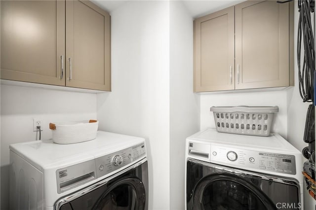 clothes washing area with cabinets and separate washer and dryer