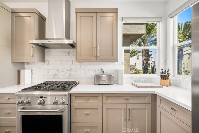 kitchen featuring wall chimney range hood, backsplash, and stainless steel range