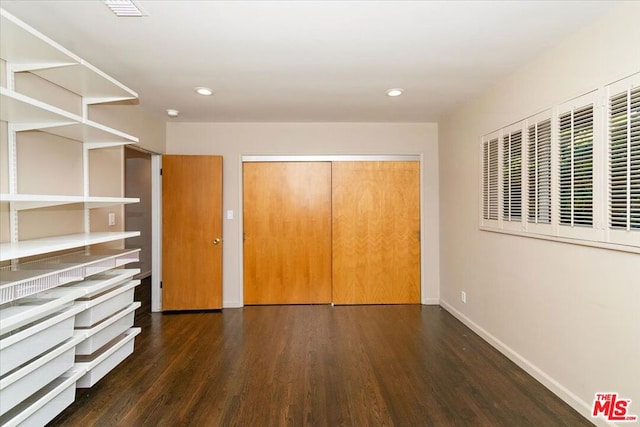 unfurnished bedroom featuring dark hardwood / wood-style floors and a closet