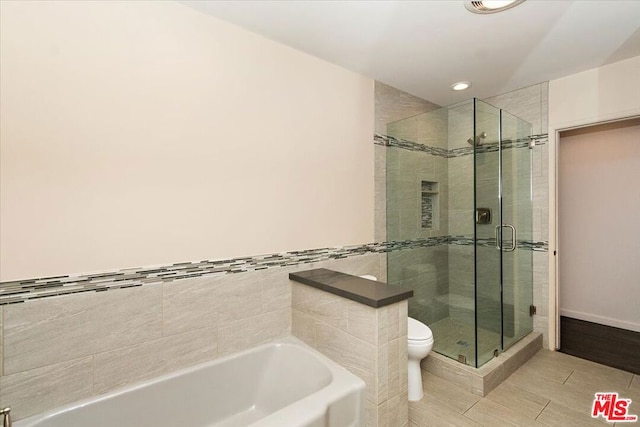 bathroom featuring tile patterned flooring, toilet, and independent shower and bath