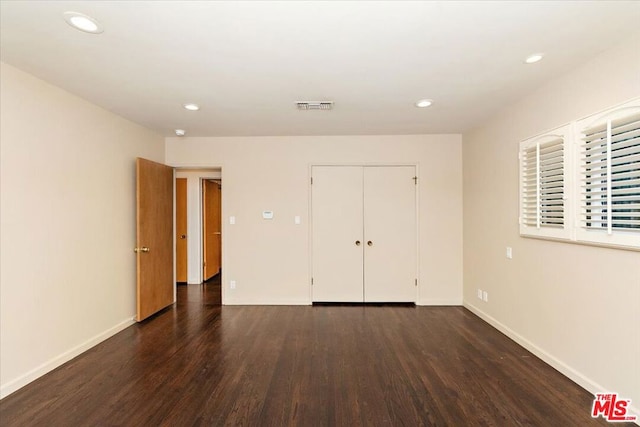 unfurnished bedroom featuring dark hardwood / wood-style flooring and a closet