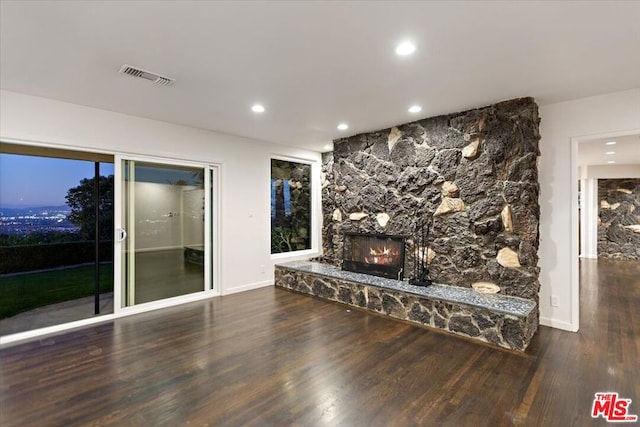 unfurnished living room featuring dark hardwood / wood-style floors and a stone fireplace