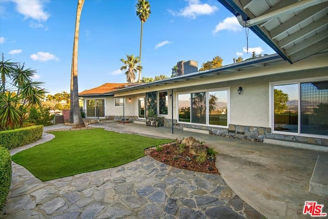 rear view of property featuring a lawn and a patio area