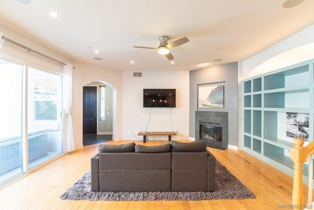 living room with a tile fireplace, hardwood / wood-style floors, a wealth of natural light, and ceiling fan