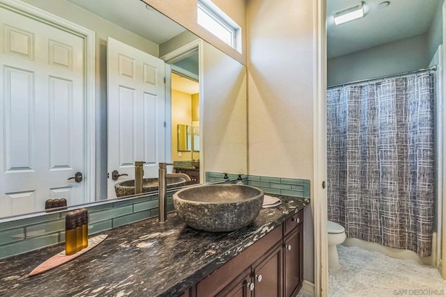 bathroom with decorative backsplash, toilet, and vanity