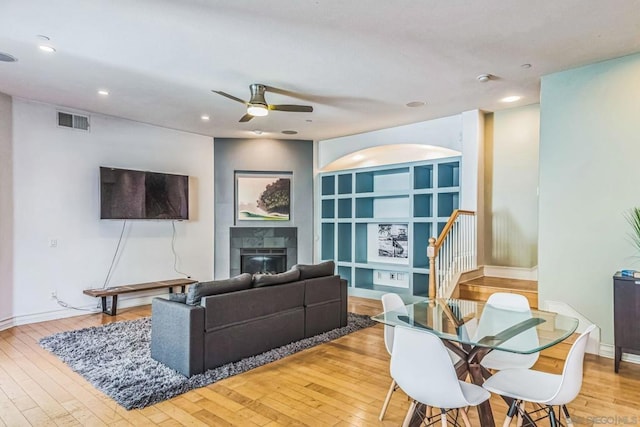 living room with ceiling fan, light hardwood / wood-style floors, and a tile fireplace