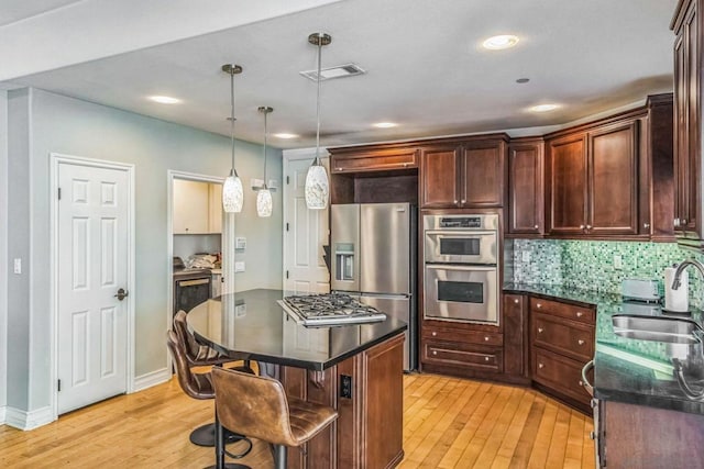 kitchen with a breakfast bar area, sink, a center island, and light wood-type flooring