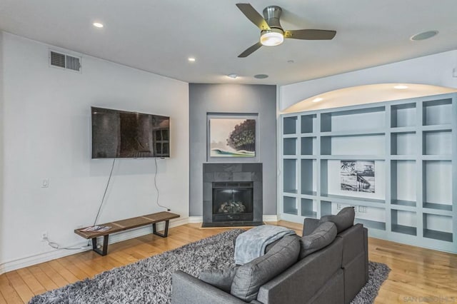 living room with a tile fireplace, hardwood / wood-style floors, and ceiling fan