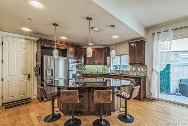 kitchen featuring backsplash, sink, decorative light fixtures, and light hardwood / wood-style flooring