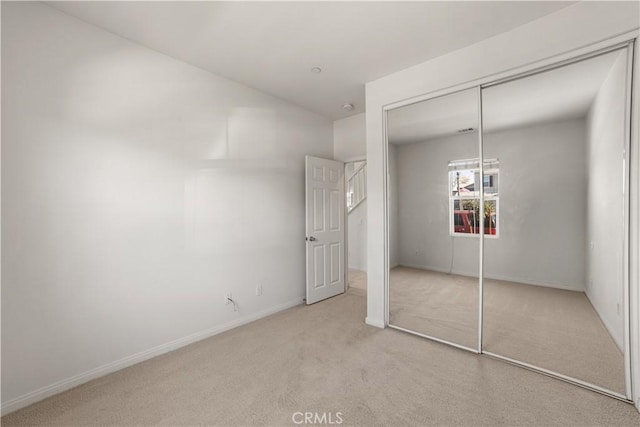 unfurnished bedroom with light colored carpet and a closet