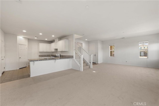 kitchen with kitchen peninsula, light carpet, and white cabinetry