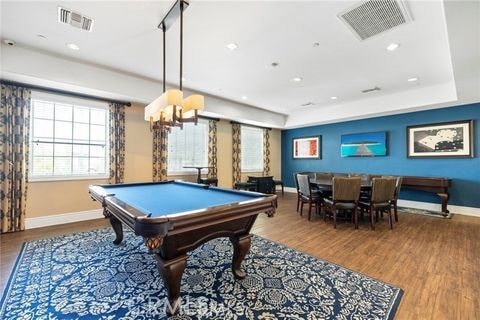 recreation room featuring a raised ceiling, hardwood / wood-style flooring, a notable chandelier, and billiards