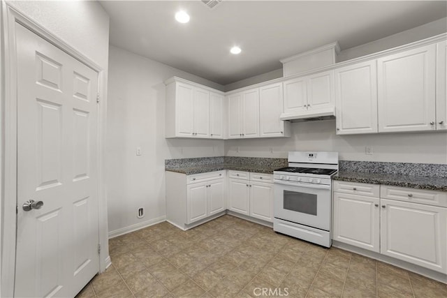 kitchen with white range with gas stovetop, white cabinetry, and dark stone counters