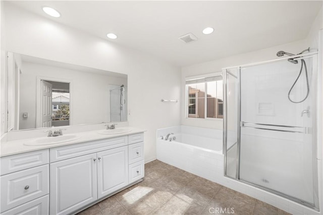 bathroom with plus walk in shower, vanity, and a wealth of natural light