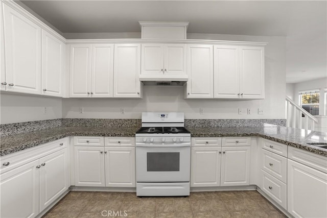 kitchen featuring white cabinetry, white stove, and dark stone counters