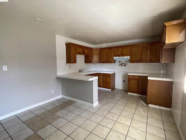 kitchen featuring kitchen peninsula, light tile patterned floors, and sink