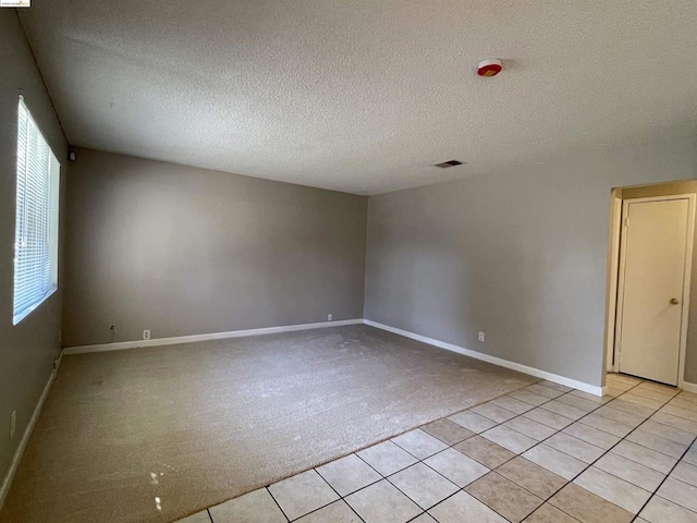 unfurnished room with light carpet and a textured ceiling