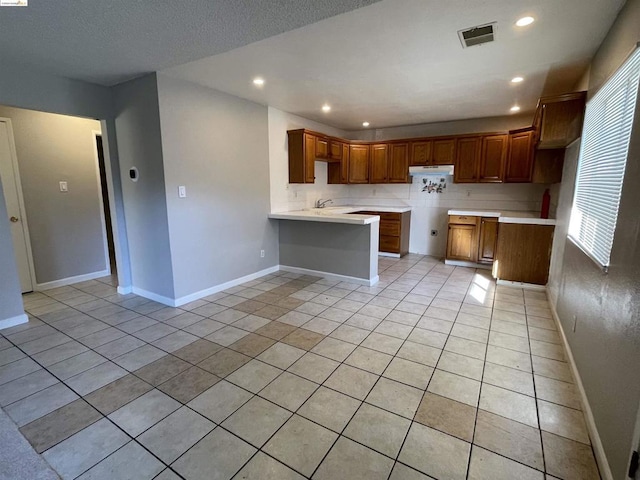 kitchen featuring kitchen peninsula, sink, a healthy amount of sunlight, and light tile patterned flooring