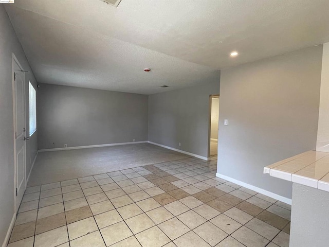 tiled empty room with a textured ceiling