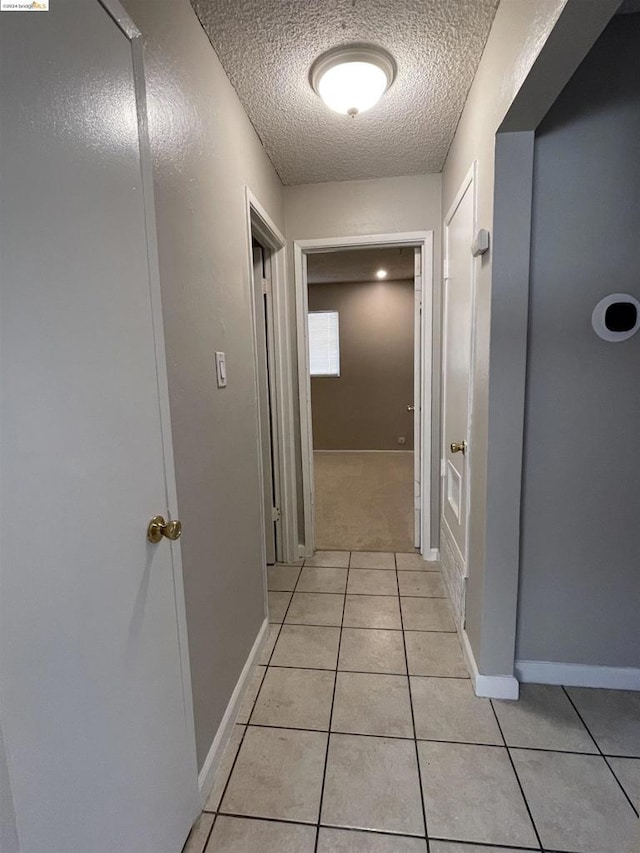 hall featuring light tile patterned floors and a textured ceiling