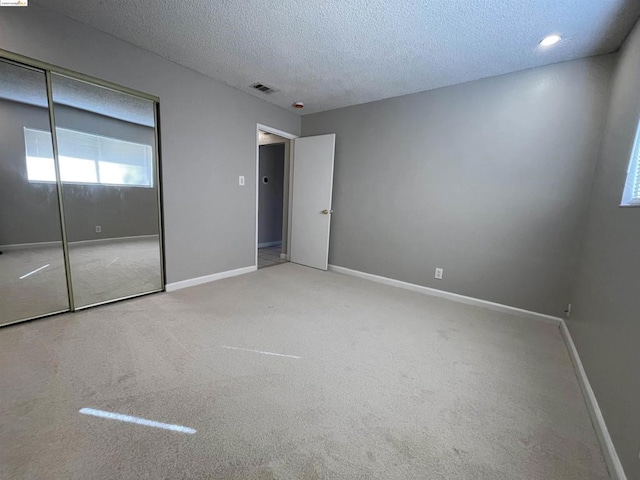 unfurnished bedroom featuring a closet, carpet floors, and a textured ceiling