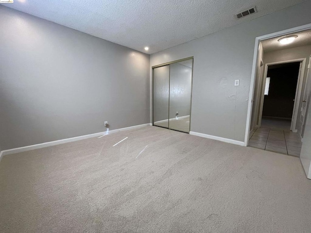 unfurnished bedroom with carpet flooring, a textured ceiling, and a closet