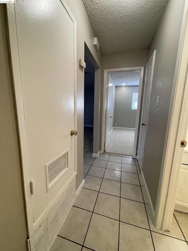 hallway featuring light tile patterned floors and a textured ceiling