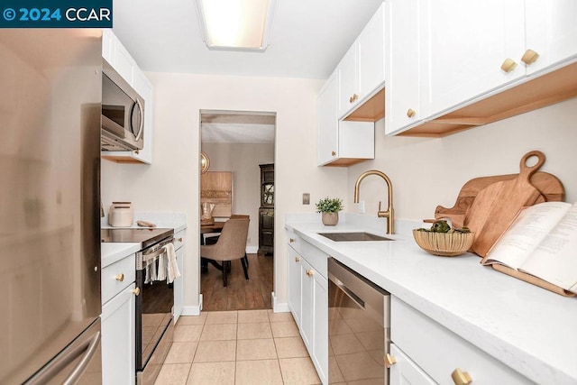 kitchen featuring sink, white cabinets, light tile patterned floors, and appliances with stainless steel finishes