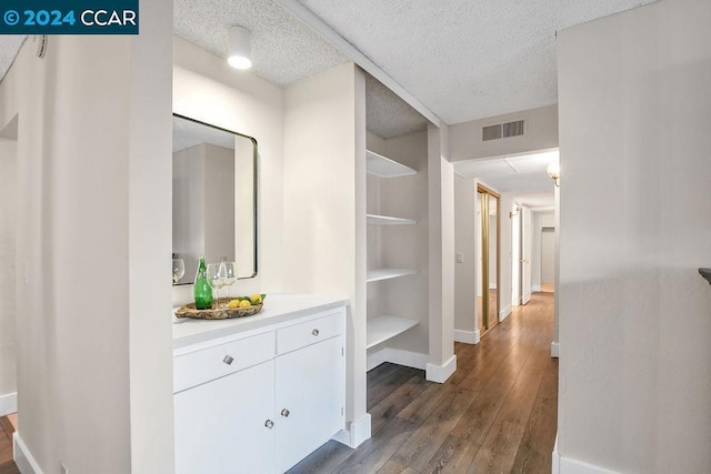 corridor featuring a textured ceiling and dark hardwood / wood-style floors