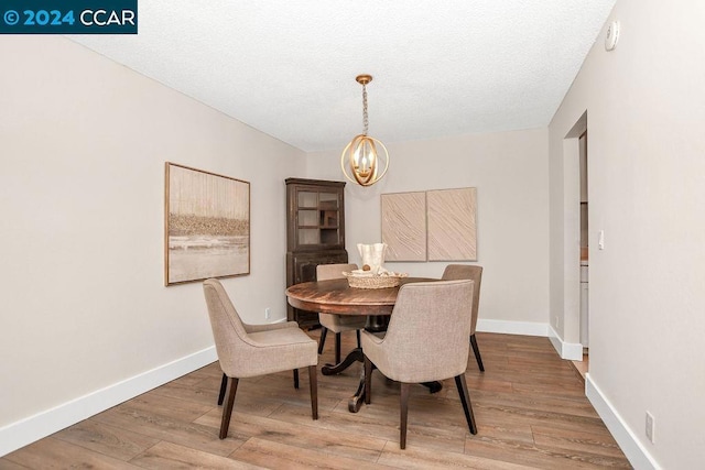 dining space featuring hardwood / wood-style floors, a textured ceiling, and a chandelier