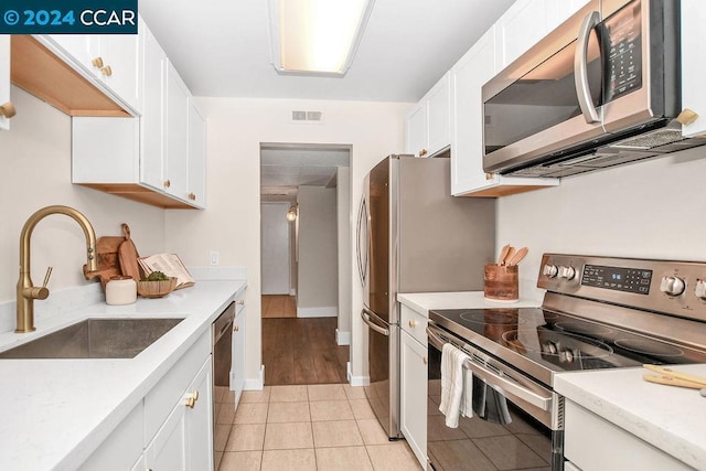 kitchen featuring white cabinetry, sink, light tile patterned floors, and stainless steel appliances