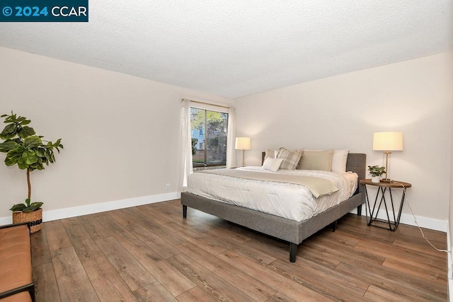 bedroom featuring wood-type flooring and a textured ceiling