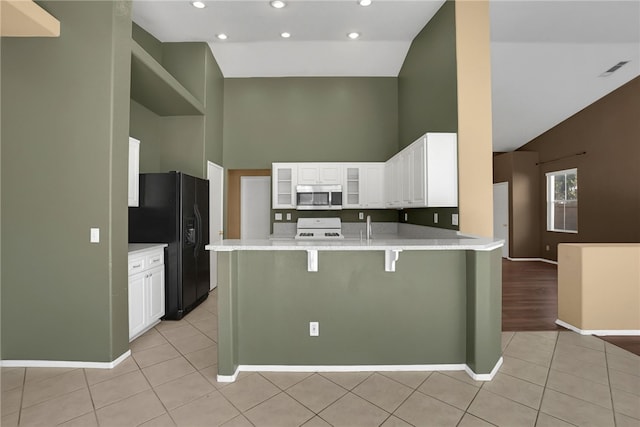 kitchen featuring kitchen peninsula, black fridge with ice dispenser, white range oven, high vaulted ceiling, and white cabinets