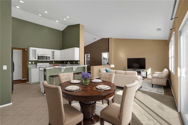 tiled dining space featuring a wealth of natural light, sink, and high vaulted ceiling