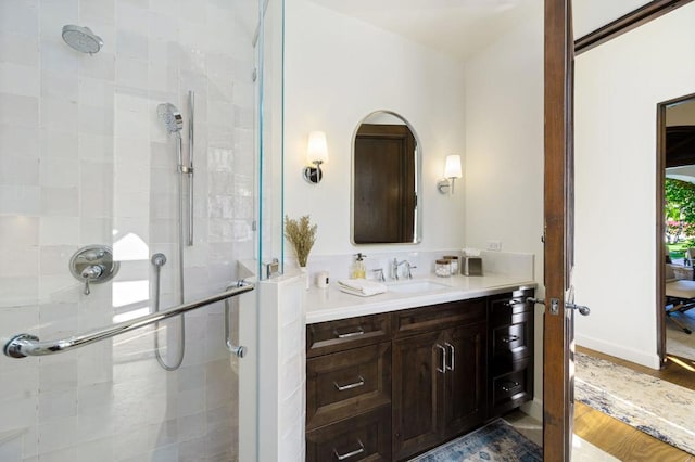 bathroom featuring a shower with door and vanity