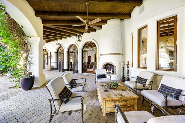 view of patio / terrace with ceiling fan and an outdoor living space with a fireplace