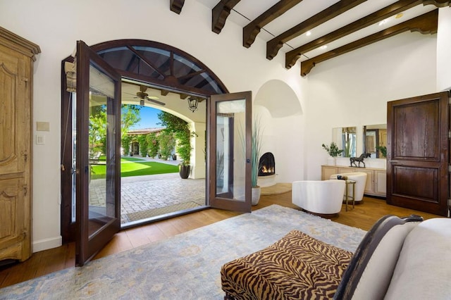 foyer entrance featuring beamed ceiling, a high ceiling, and light wood-type flooring