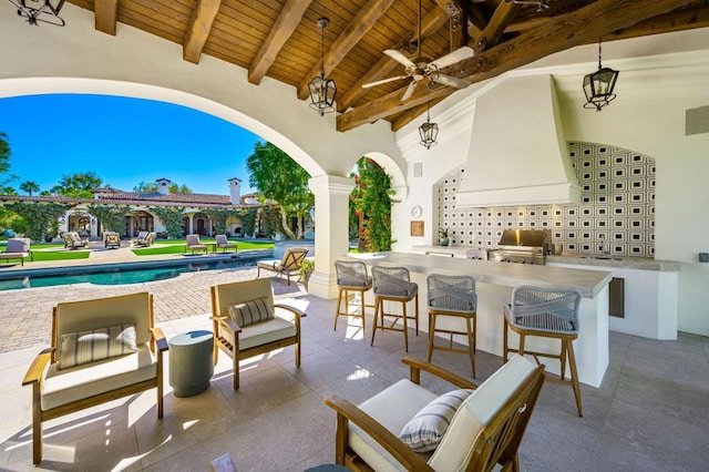 view of patio / terrace featuring ceiling fan, grilling area, exterior bar, and exterior kitchen