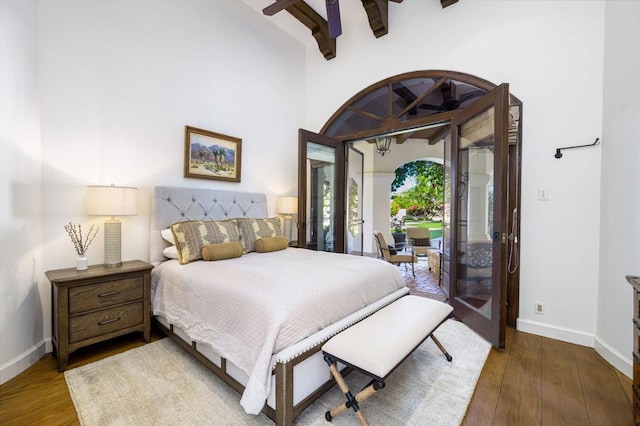 bedroom with beam ceiling, access to exterior, hardwood / wood-style flooring, and french doors