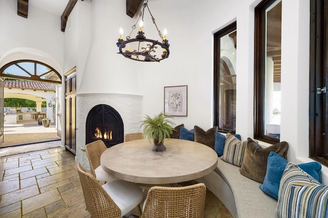 dining room with a high ceiling, plenty of natural light, a notable chandelier, and beam ceiling