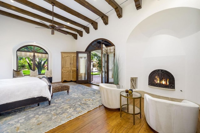 bedroom featuring access to exterior, hardwood / wood-style flooring, and beamed ceiling