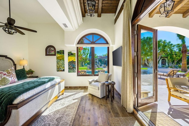 bedroom with beamed ceiling, hardwood / wood-style floors, and access to outside