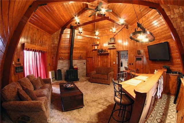 carpeted living room with a wood stove, wooden walls, beamed ceiling, and wood ceiling