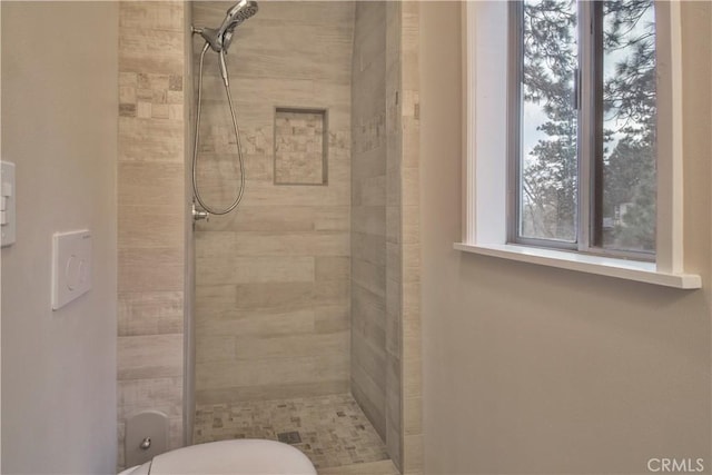 bathroom featuring a tile shower and toilet